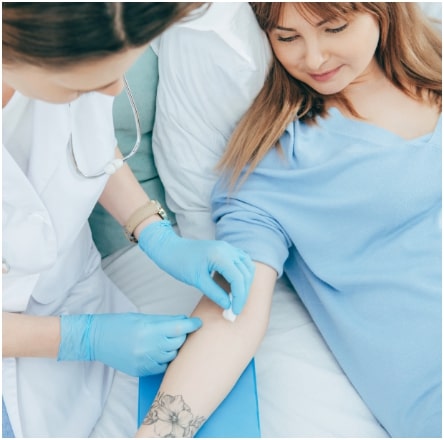 A woman is getting her arm injected by a nurse.